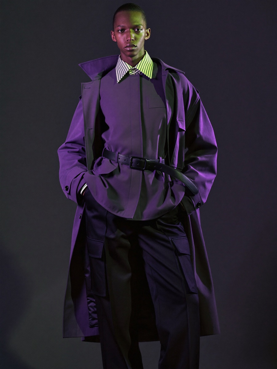 Model in avant-garde dark streetwear lit with violet and lime studio lighting