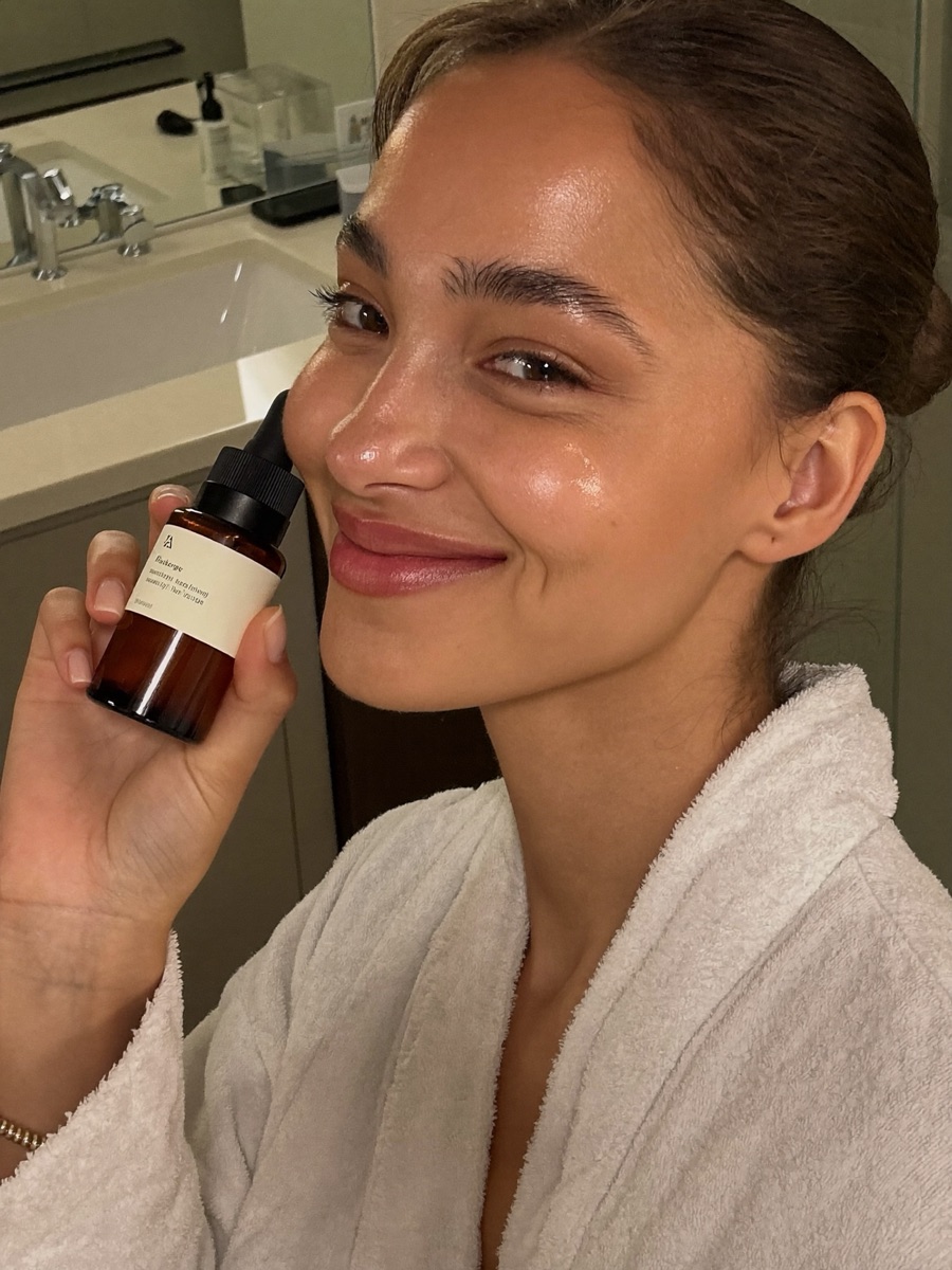 UGC-style beauty creator holding a serum bottle in soft vanity lighting
