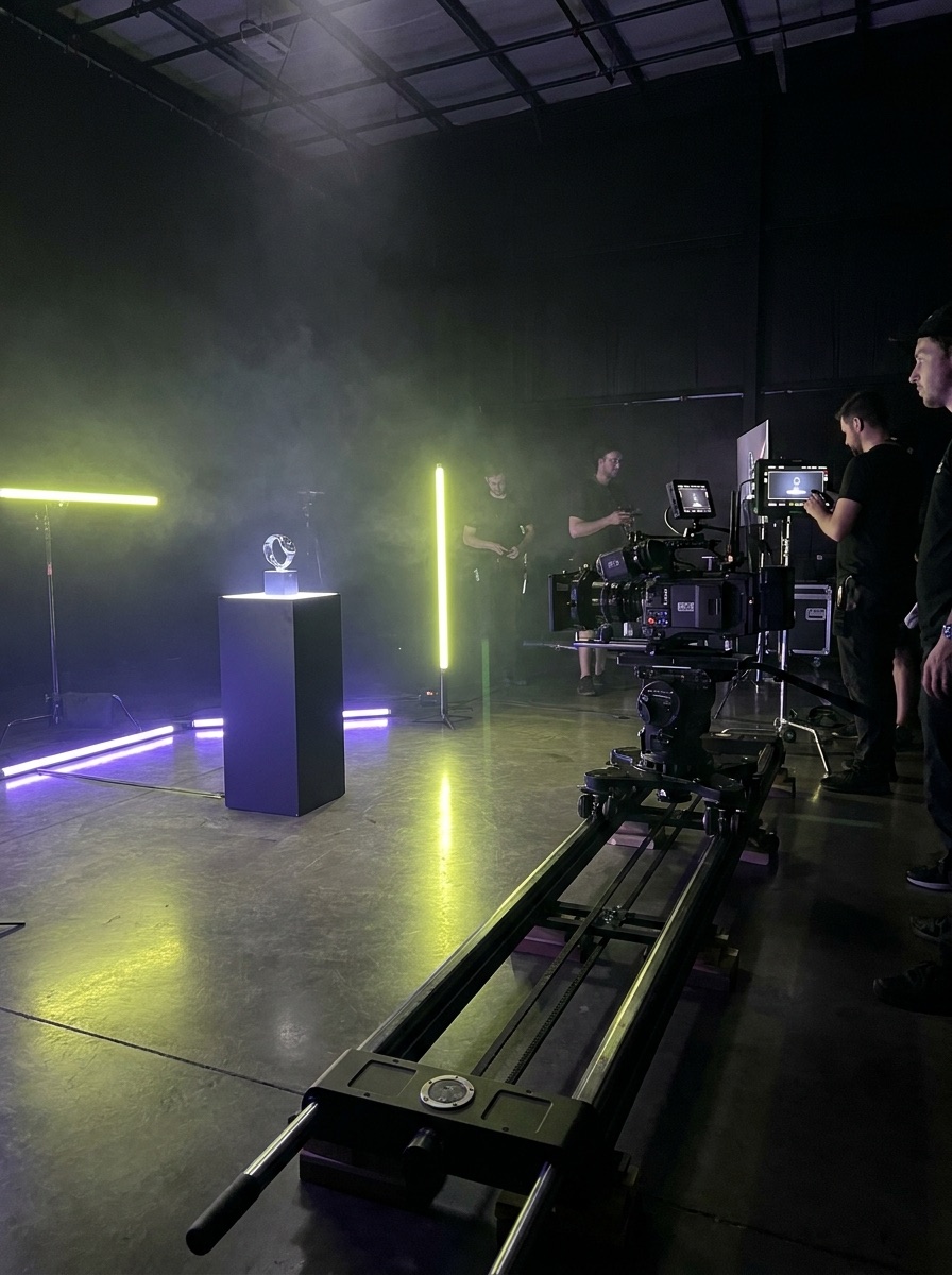 Cinema camera on a slider in a dark studio lit with electric lime and violet lights
